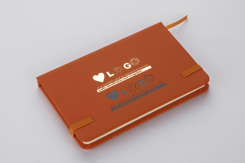 Notes VITAL A6
Gustowny notes A6 z kolorową gumką wykonany z ekoskóry PU. Notes zawiera 80 kartek ecru w linie koloru pomarańczowego. Logo nadrukujemy na okładce.